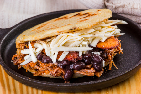 Delicious arepa stuffed with white cheese, fried plantain, roasted meat and black beans, Latin American foodの写真素材