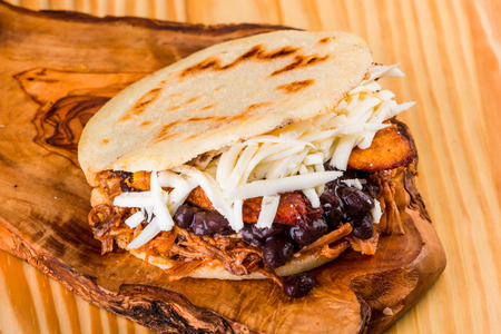 Delicious arepa stuffed with white cheese, fried plantain, roasted meat and black beans, Latin American foodの写真素材