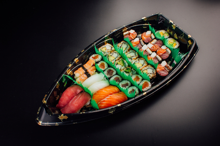 Japanese cuisine. Sushi set on a plastic ship over dark background.の写真素材