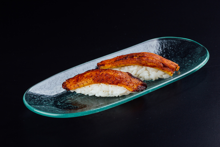 Plate with two fried plantain nigiris on black backgroundの写真素材