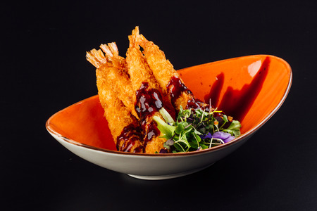 Traditional japanese tempura shrimps with sauce, deep fried shrimps top view on the dark backgroundの写真素材