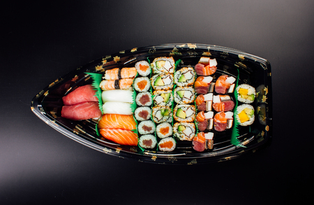 Japanese cuisine. Sushi set on a plastic ship over dark background.の写真素材