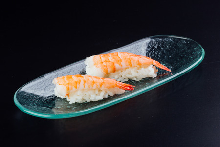 Plate with two fresh shrimp nigiris on black backgroundの写真素材