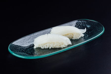 Plate with two fresh cuttlefish nigiris on black backgroundの写真素材