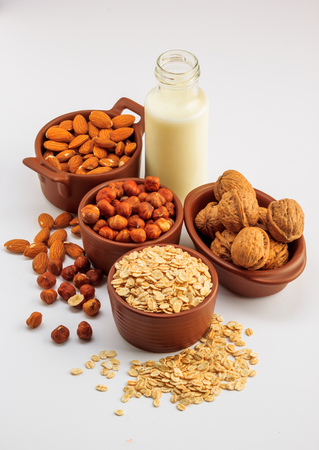 Different types of vegan milk, almond milk, oat milk, hazelnut milk and walnut milk on a white backgroundの写真素材