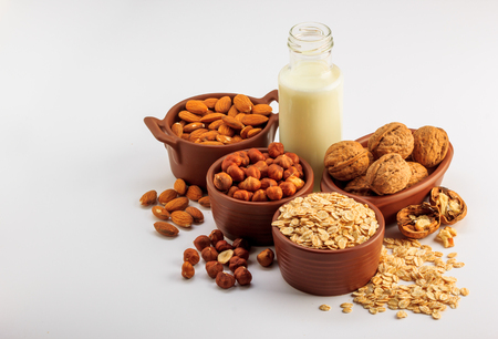 Different types of vegan milk, almond milk, oat milk, hazelnut milk and walnut milk on a white backgroundの写真素材