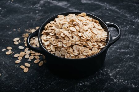 Top view of a black bowl with oat flakes on a black background. healthy food concept.の写真素材