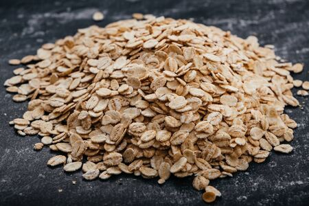 Pile of oat flakes on a black background.