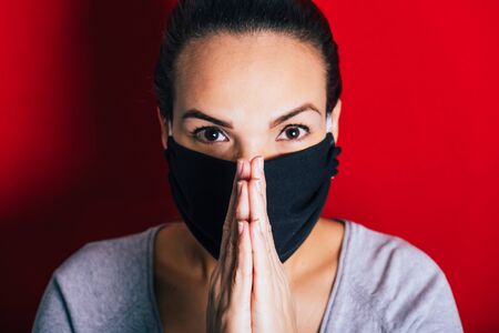 Woman with mask praying for the elimination of the coronavirus pandemic.