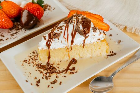Three milk cake with chocolate syrup and some strawberriesの写真素材