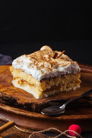 Piece of cake three milk prepared at home. The image is made on a dark background and rustic boards. Latin American dessertの写真素材