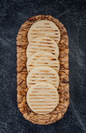 Top view of woven basket filled with a group of Latin American arepas on a dark backgroundの写真素材