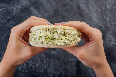 Woman holding a pepeada queen arepa typical of Venezuelan cuisine.