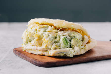 Typical Venezuelan arepa de reina pepeada on a wooden boardの写真素材