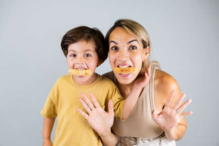 Mother and son enjoying and eating a Latin American snack called tequeÃ±os, funny expressions on their facesの写真素材