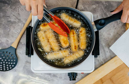 Latin american cook preparing and frying venezuelan tequeÃ±os, latin appetizerの写真素材