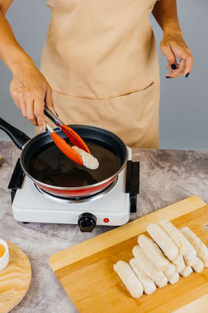 Latin american cook preparing and frying venezuelan tequeÃ±os, latin appetizer