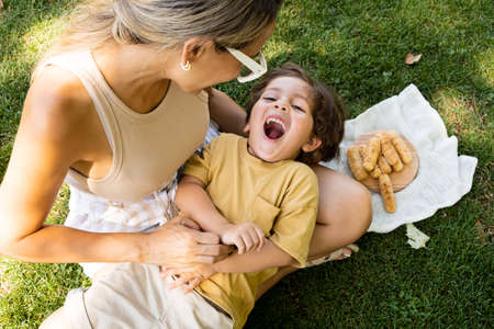 Mother and son enjoying and eating a Latin American snack called tequeÃ±os, funny expressions on their facesの写真素材