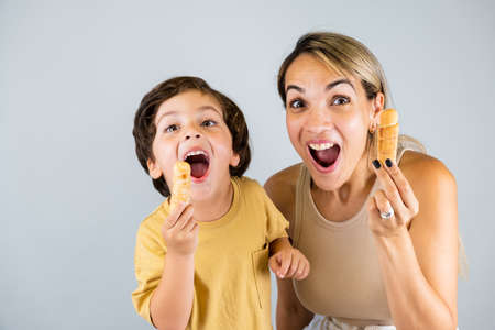 Mother and son enjoying and eating a Latin American snack called tequeÃ±os, funny expressions on their facesの写真素材