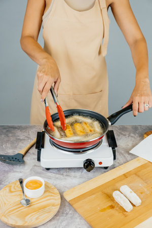 Latin american cook preparing and frying venezuelan tequeÃ±os, latin appetizerの写真素材