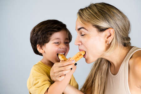 Mother and son enjoying and eating a Latin American snack called tequeÃ±os, funny expressions on their facesの写真素材