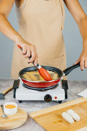 Latin american cook preparing and frying venezuelan tequeÃ±os, latin appetizerの写真素材
