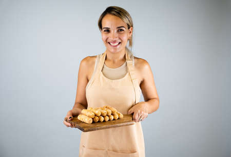 Latin girl holding a wooden board with freshly cooked tequeÃ±os, typical Venezuelan foodの写真素材