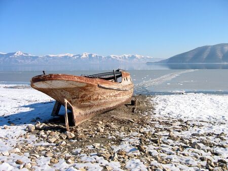 Old lonely boat abandoned at snowy coastの写真素材