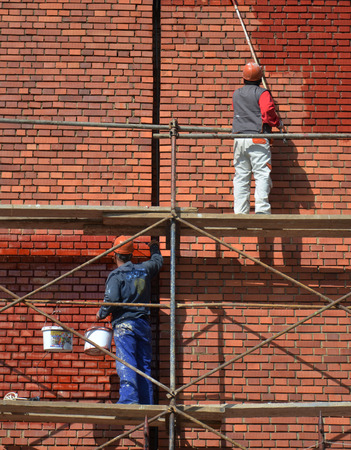Men painting red brick wallの写真素材