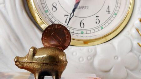 Coin on   vintage piggy bank against clockの写真素材
