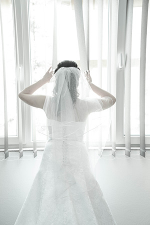 Bride on a window looking for a groom. Wedding conceptの写真素材