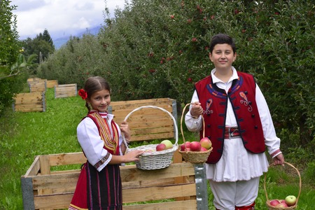 RESEN, MACEDONIA. 27 SEPTEMBER 2015- Boy and girl in traditional clothes posing with apples during festival Prespa apple picking festival 2015 in Resen, Macedoniaのeditorial素材