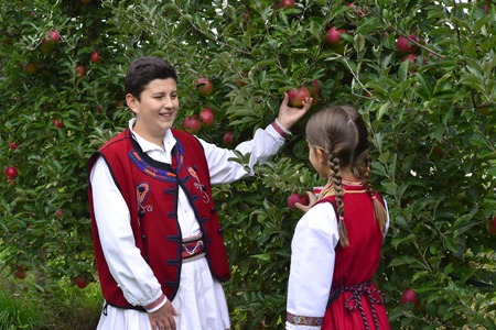 RESEN, MACEDONIA. 27 SEPTEMBER 2015- Boy and girl in traditional clothes posing with apples during festival Prespa apple picking festival 2015 in Resen, Macedoniaのeditorial素材