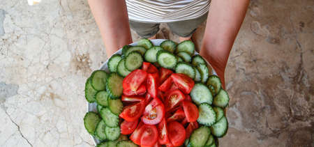 Plate Fresh tomato and cucumber salad plate in a handsの写真素材
