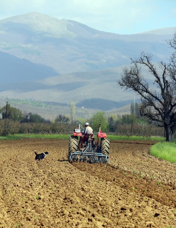 picture of a man in tractor plowing field in springの写真素材