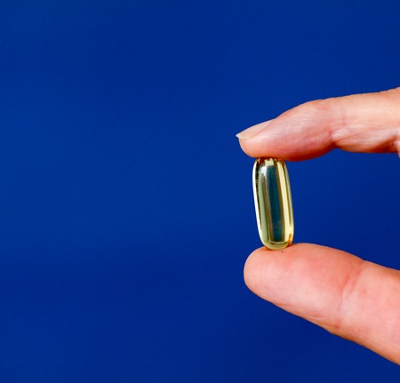 picture of a Cod liver oil omega 3 gel capsule between fingersの写真素材
