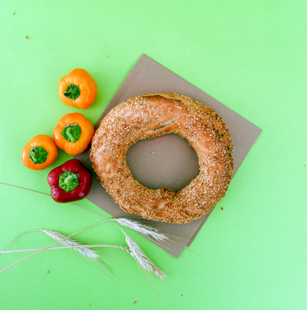 Turkish bagel simit , wheat ears and chili paprika on green