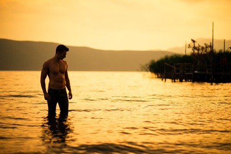 Muscle wet sexy young boy posing in lakeの写真素材