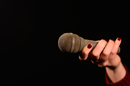 woman hands holding dirty and dusty microphone on a dark backgroundの写真素材