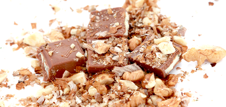 close up a stuffed chocolate bar and walnut pieces on white backgroundの写真素材