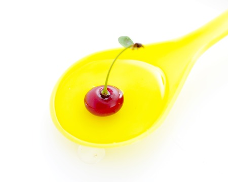 organic sour cherry in a plastic yellow spoon on white background,image of aの写真素材