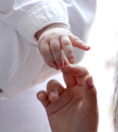 Baby hand gently holding girl fingersの写真素材