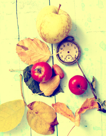apples,clock, leaves, on blue paint wood background,autumn concept,yellow effect addedの写真素材