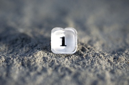 plastic translucent button number one from an old calculator on a concrete backgroundの写真素材
