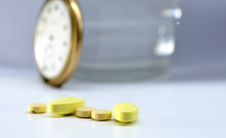 various pills and vintage clock on white backgroundの写真素材