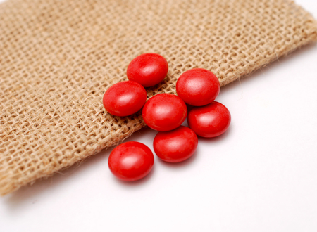 multivitamin red pills on a jute bag background