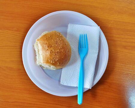 bread with sesame seeds on a disposable plate.