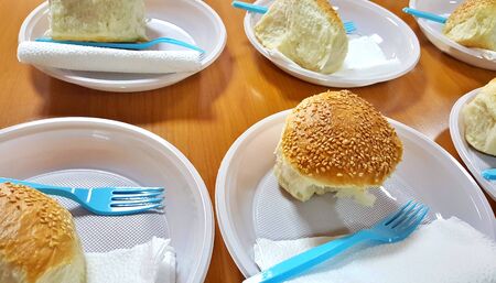 bread with sesame seeds on a disposable plate.