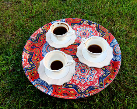 The cup of coffee on a morning grass image