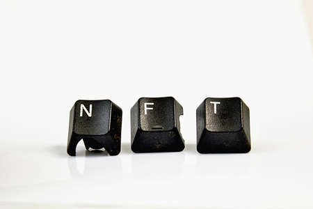 NFT text with used black computer keys on white.の写真素材